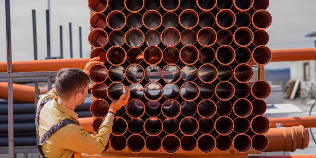 workman arranging pipes for manufacturing use