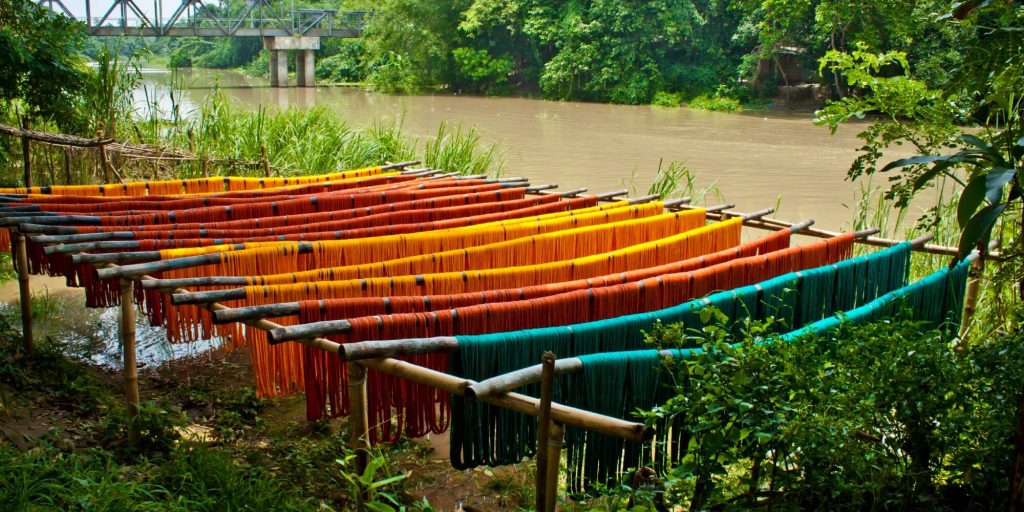 colorful fabric dyeing by a river in thick rainforest