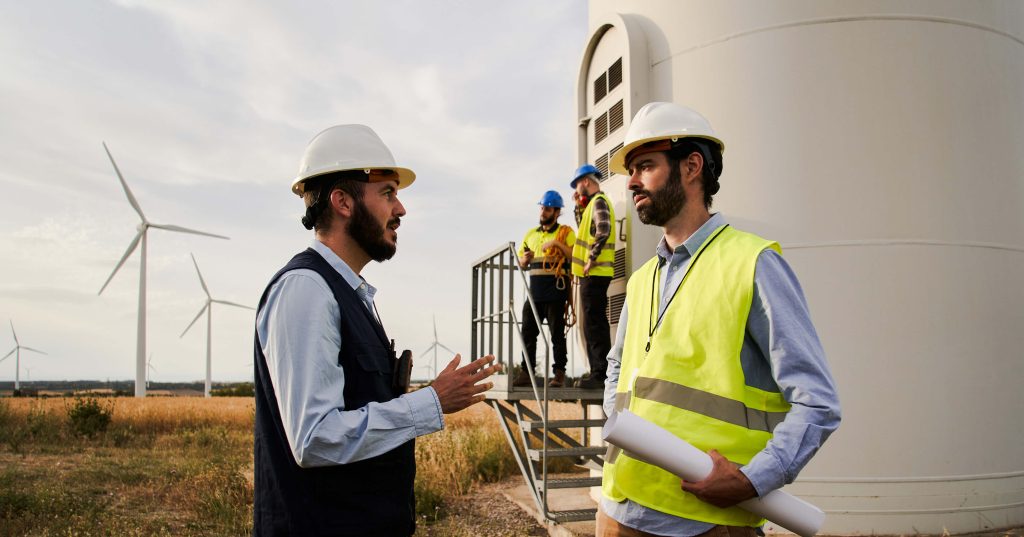 engineers in high visibility vests at the base of a windmill
