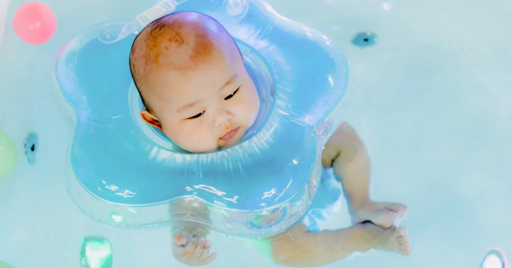 Image of an Asian baby boy wearing a swimming float and learning to swim in bathtub
