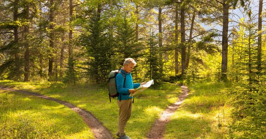 man in forest checking route on paper map