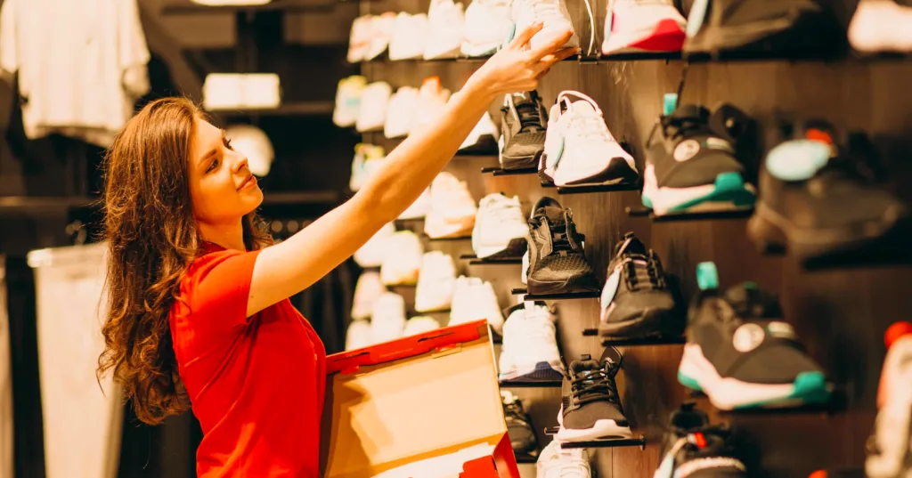 sales assistant in sporting goods store restocks sneakers