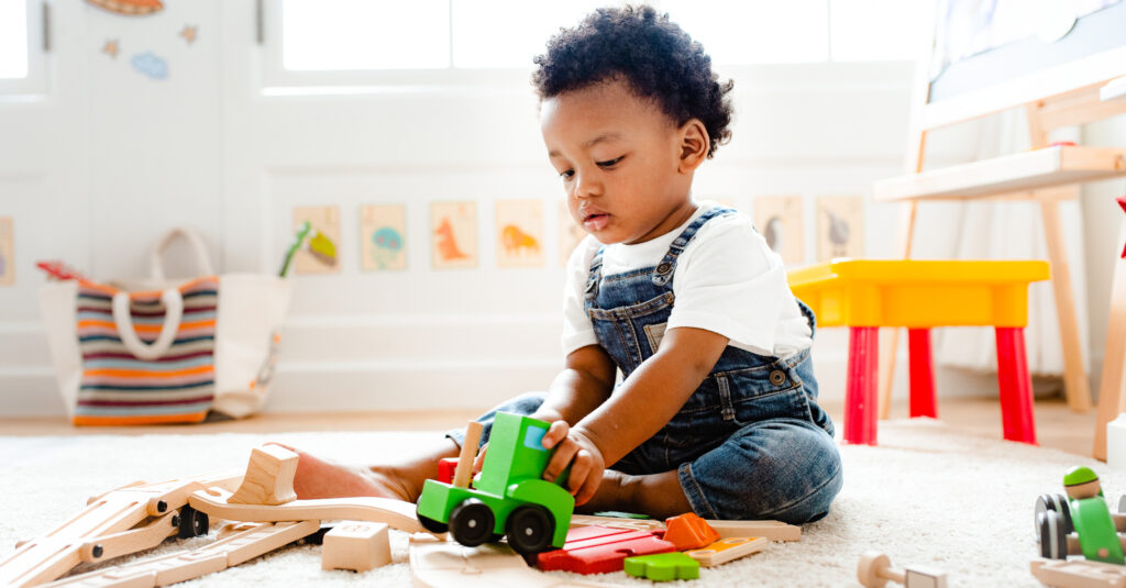 young boy playing with toy train set
