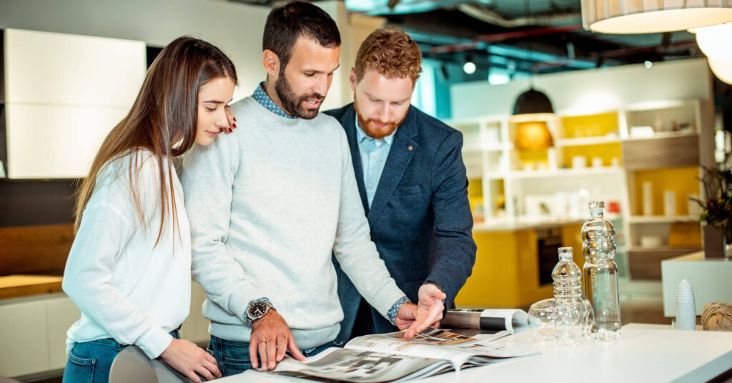 customers and sales assistant looking at product catalog in furniture showroom