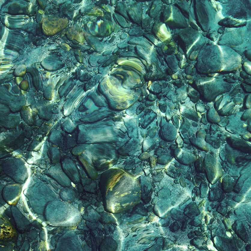 clear pool of water with visible stones in the sunlight