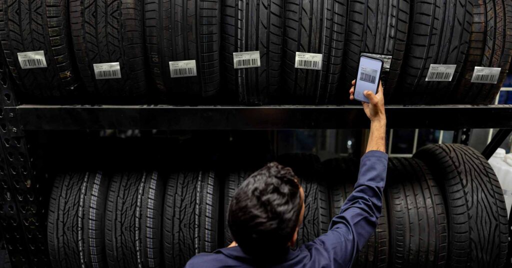 worker scanning barcodes on tires in warehouse