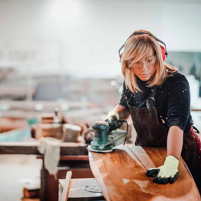 Woodworker using a hand sander to sand down a wooden surface