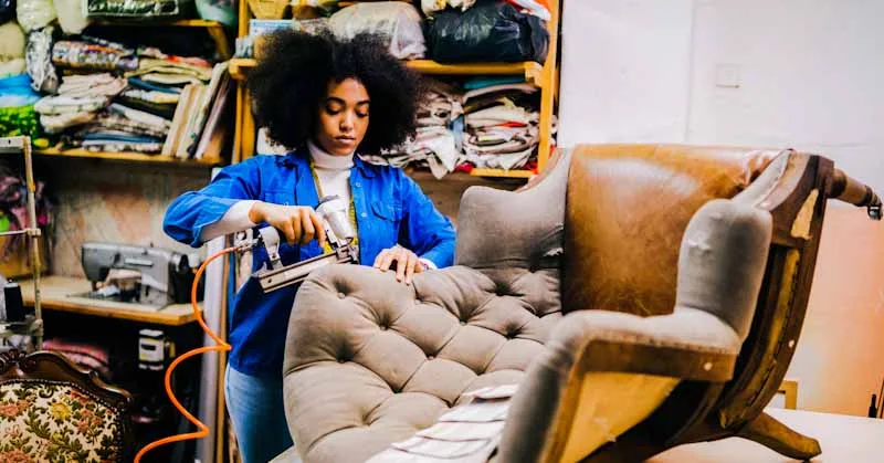 female furniture maker upholstering vintage chair