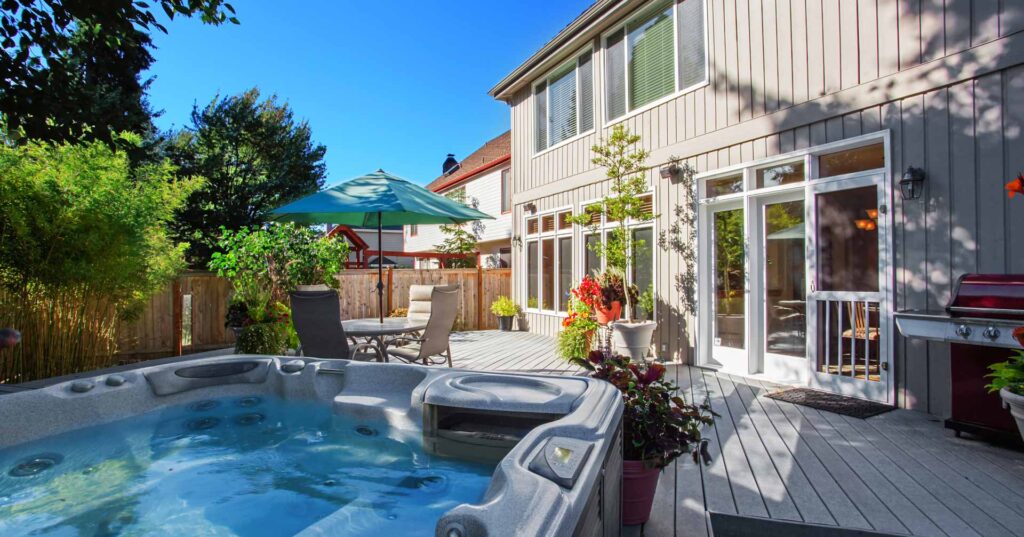 Cozy backyard with patio area and hot tub. Walkout deck with flower pots