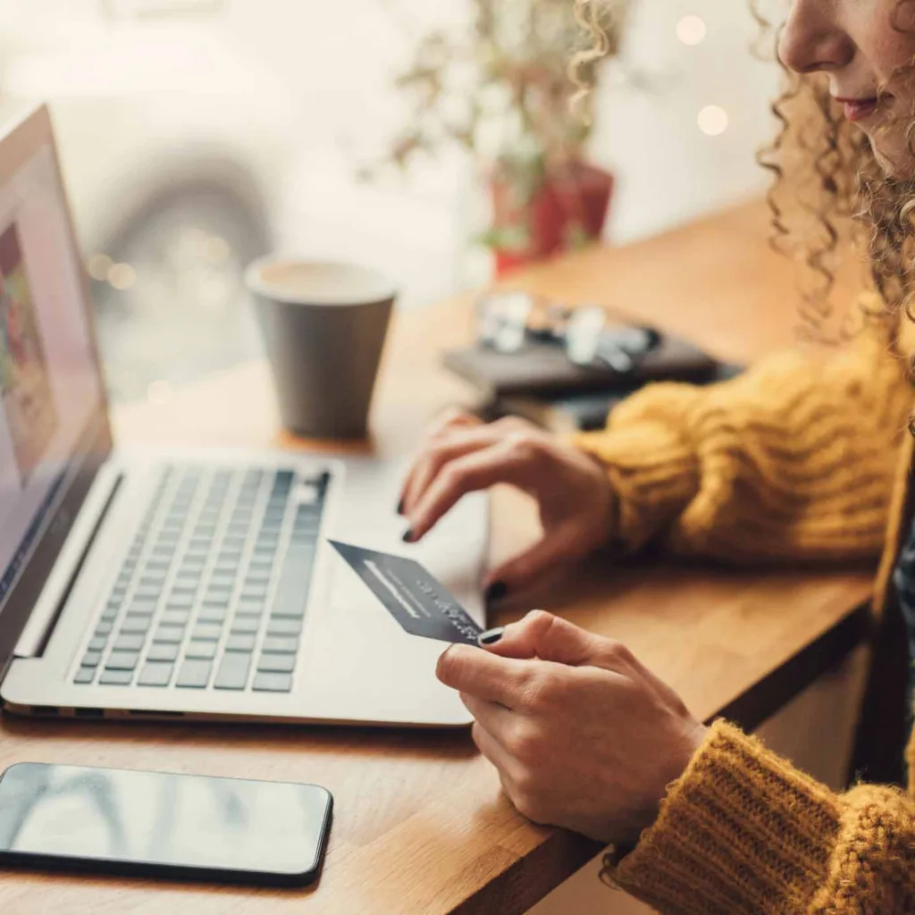 Woman in cafe using credit card and laptop