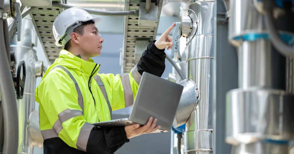 An engineer is meticulously checking the chilled water fan coil unit of an air conditioner at an industrial facility, ensuring proper operation.