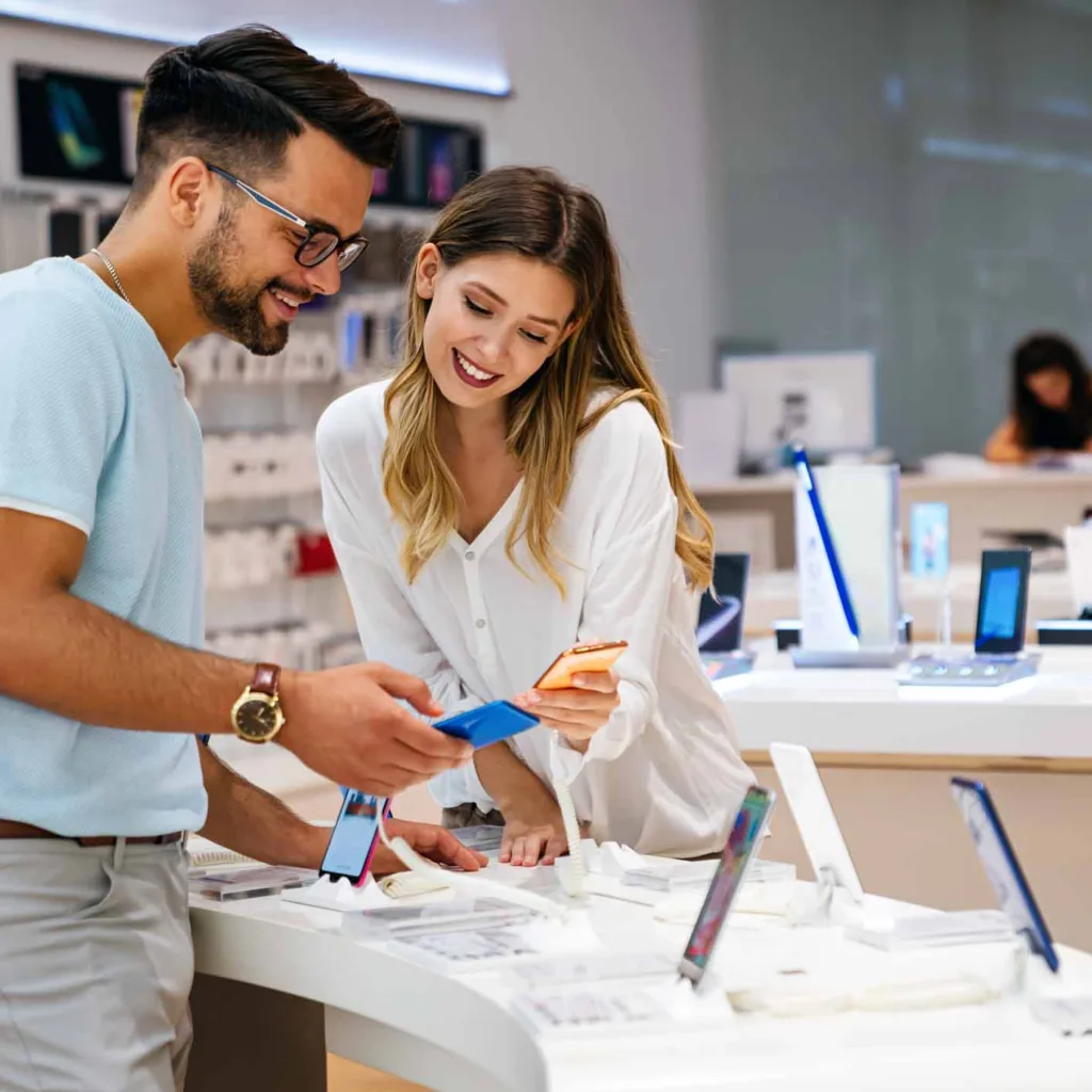 Happy couple buying a mobile phone in store.