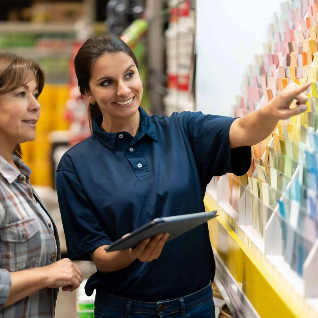 Woman at a home improvement store choosing paint colors and talking to the saleswoman about her options