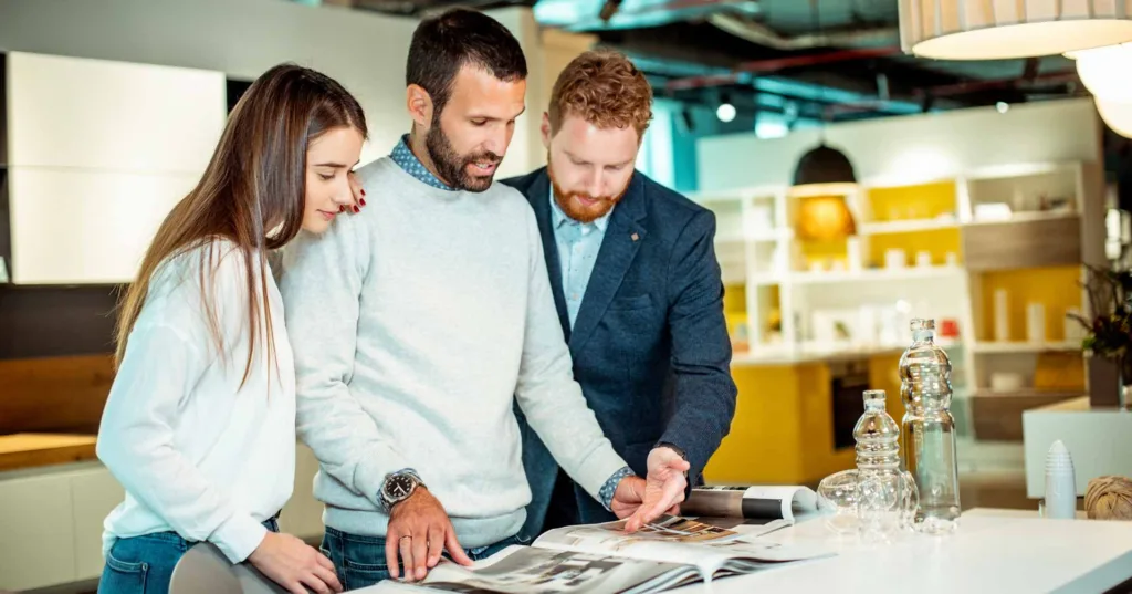 Husband and wife planning their kitchen renovation in a home supplies shop with the help of a store salesman.