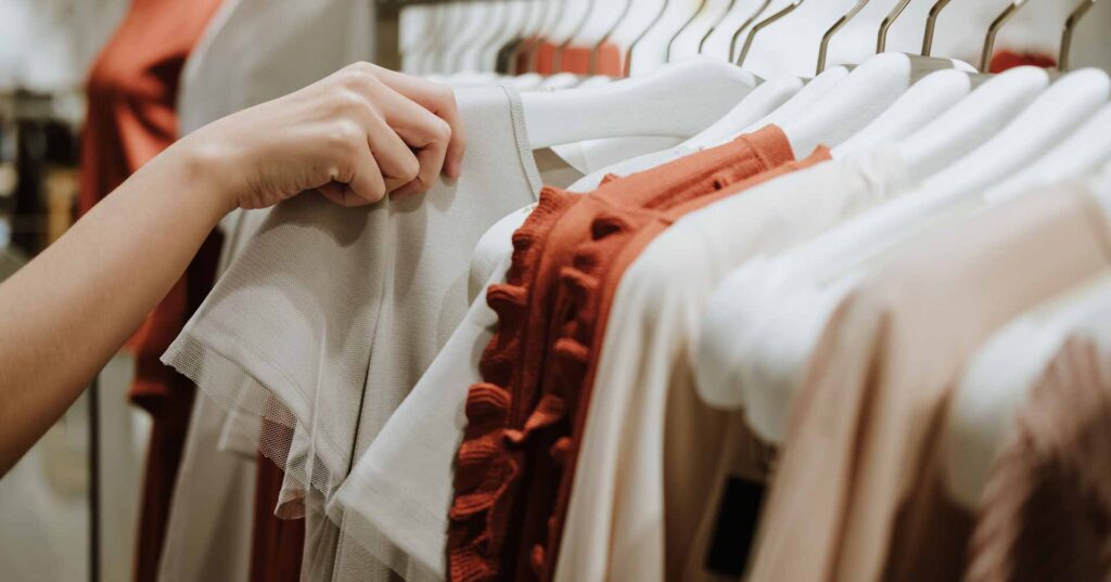 woman shopping on clothes rack in fashion store