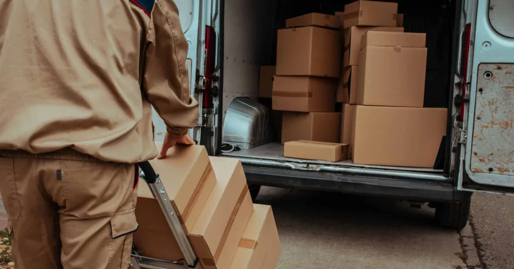 Courier packing cardboard boxes in van and preparing them for delivery