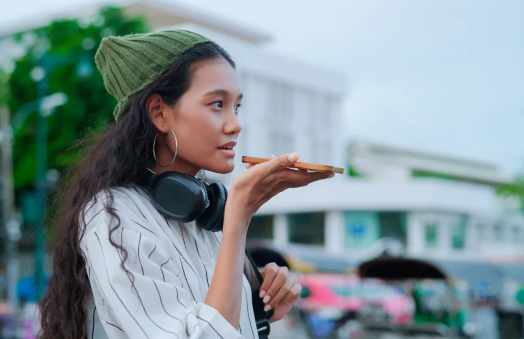 A woman talks into her mobile, shown as an example of how users may now be searching for product information using AI chatbots
