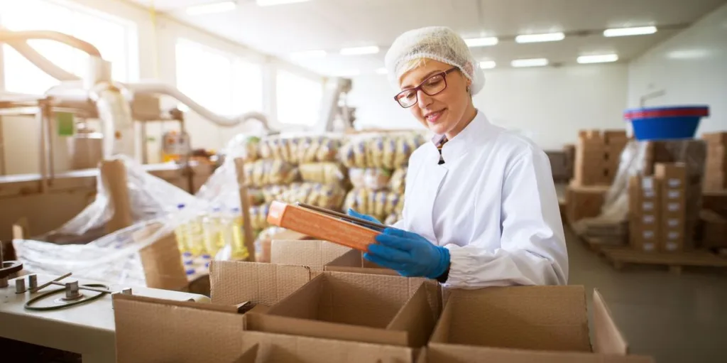 young female worker packing finished food products in boxes