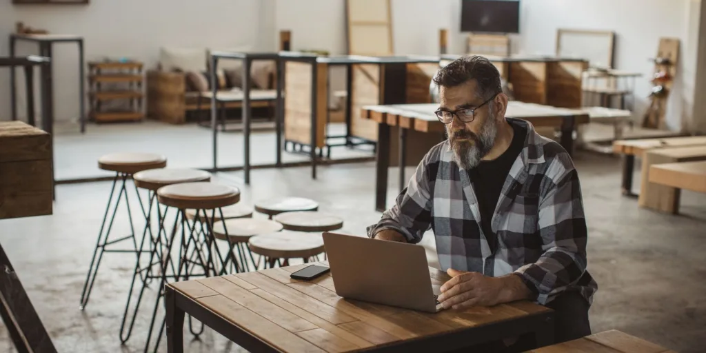 Carpenter in his furniture showroom working on laptop 